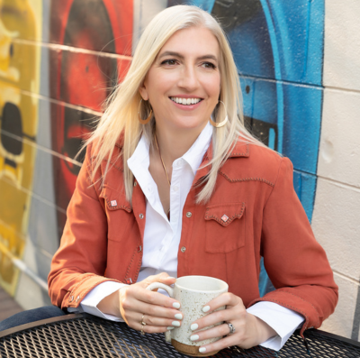 Branding photography of woman outside in orange jacket drinking coffee