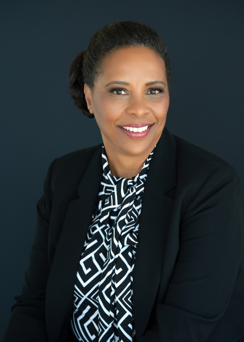 Black executive woman in blazer with dark gray background