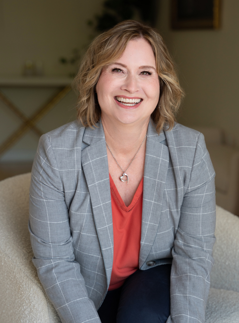 Woman in gray blazer, orange shirt in office setting for branding photograph